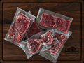 The Steak Sampler from Pierce Land & Bison showing five vacuum-sealed packages of grass-fed bison steaks including flat iron, top sirloin, filet mignon, New York strip, and ribeye on a dark walnut cutting board